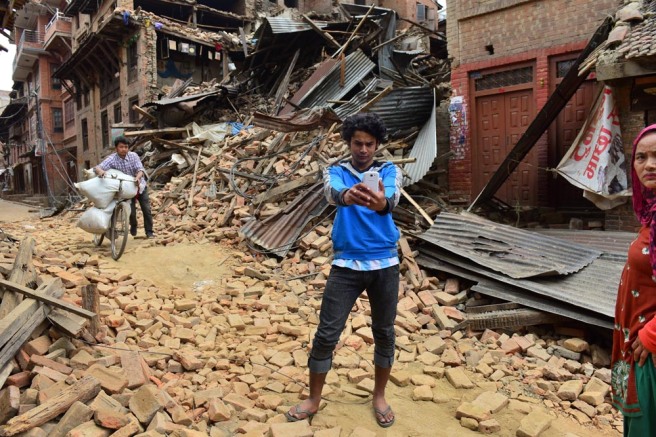 A young man takes a selfie outside a damaged house in Bhaktapur, Nepal.